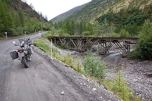 Une moto est garée sur l'épaule de la route poussiéreuse de la Kolyma en Russie