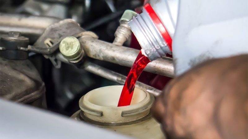 Persona añadiendo líquido de transmisión al vehículo usando un embudo